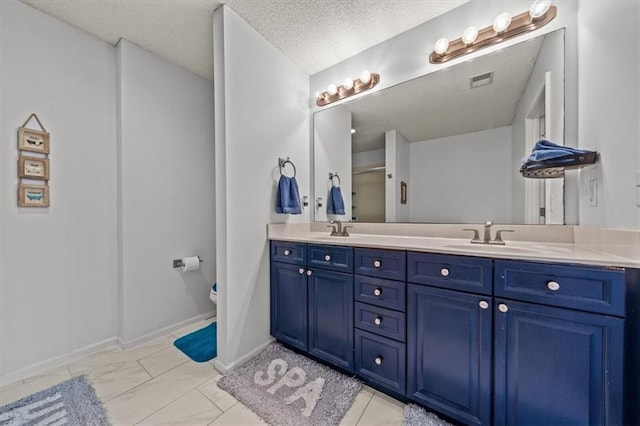 bathroom with a shower stall, double vanity, marble finish floor, a textured ceiling, and a sink