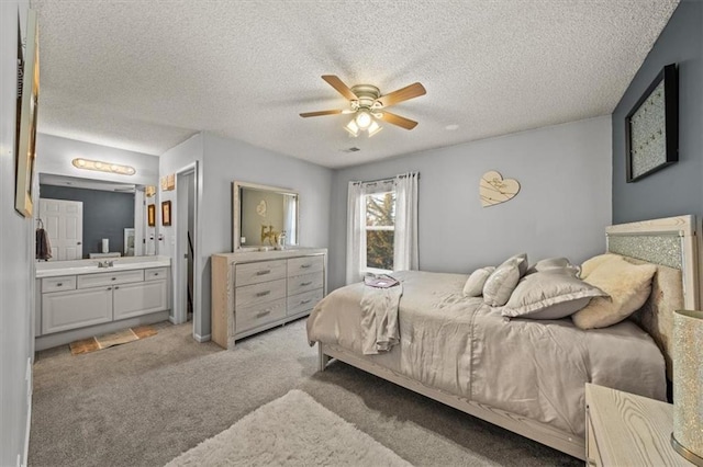 bedroom featuring light carpet, a textured ceiling, ensuite bath, and a ceiling fan