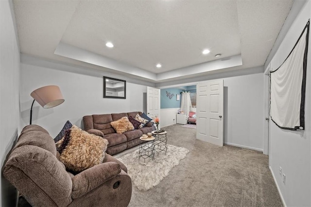 living room featuring a tray ceiling, carpet flooring, recessed lighting, and baseboards