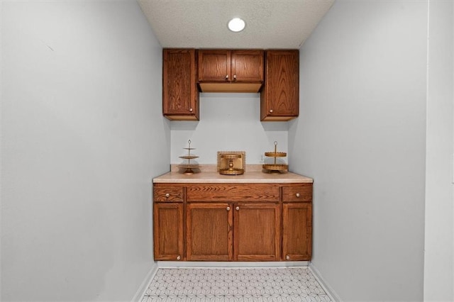 kitchen with light countertops, brown cabinetry, and baseboards