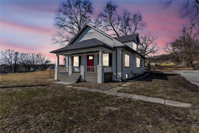 bungalow-style house featuring covered porch and a front yard