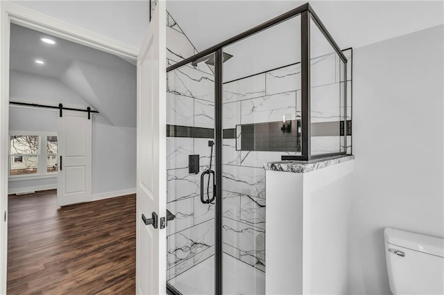 bathroom featuring toilet, a marble finish shower, wood finished floors, and lofted ceiling