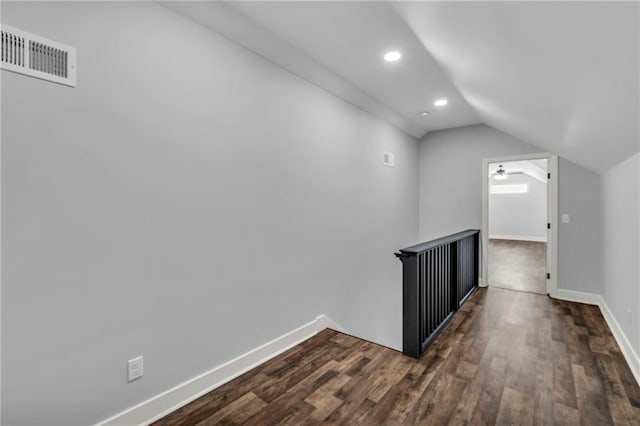 hallway featuring lofted ceiling, recessed lighting, dark wood-type flooring, visible vents, and baseboards