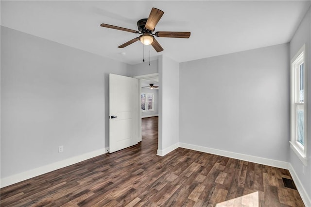 unfurnished bedroom featuring dark wood-style flooring, visible vents, ceiling fan, and baseboards