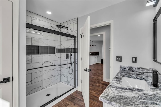 bathroom featuring baseboards, vanity, a marble finish shower, and wood finished floors