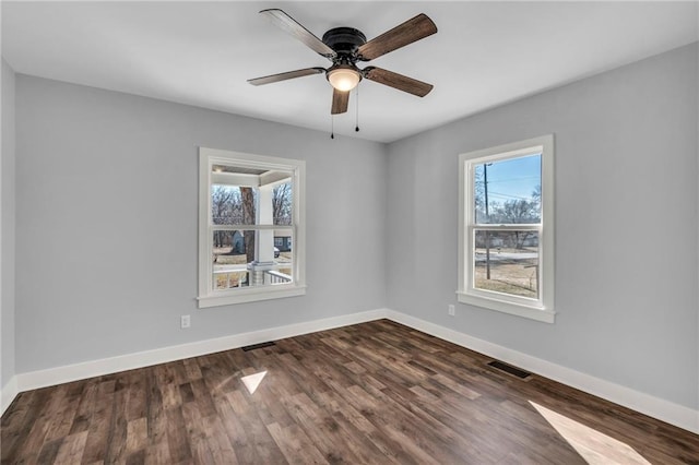 unfurnished room with baseboards, visible vents, dark wood finished floors, and a ceiling fan