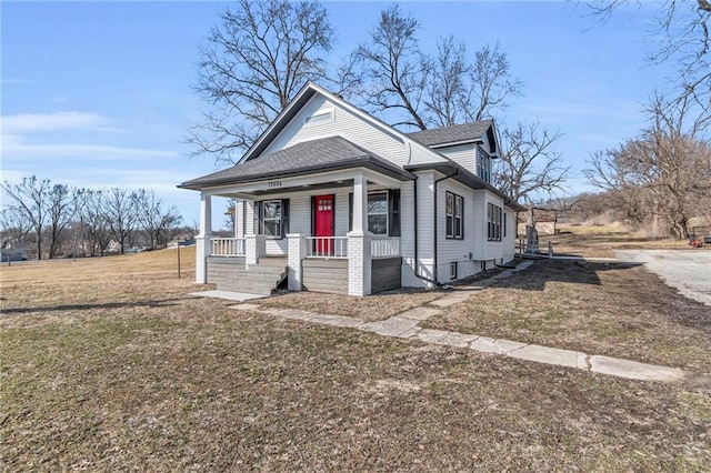 bungalow-style house with covered porch, roof with shingles, and a front lawn