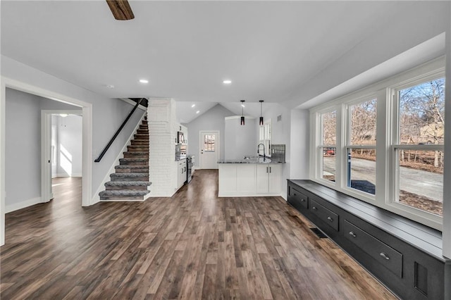 unfurnished living room featuring baseboards, dark wood-style floors, stairway, vaulted ceiling, and recessed lighting