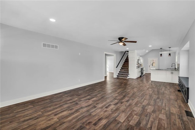 unfurnished living room featuring dark wood-style flooring, recessed lighting, visible vents, a sink, and stairs