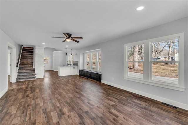 unfurnished living room featuring dark wood-style flooring, recessed lighting, visible vents, stairway, and baseboards