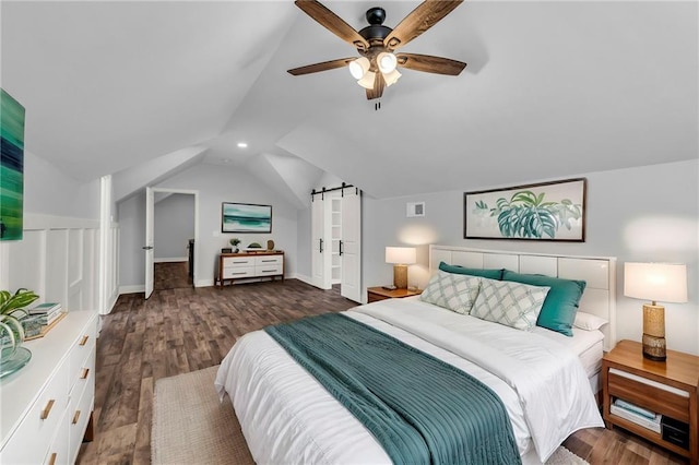 bedroom featuring ceiling fan, a barn door, visible vents, vaulted ceiling, and dark wood finished floors