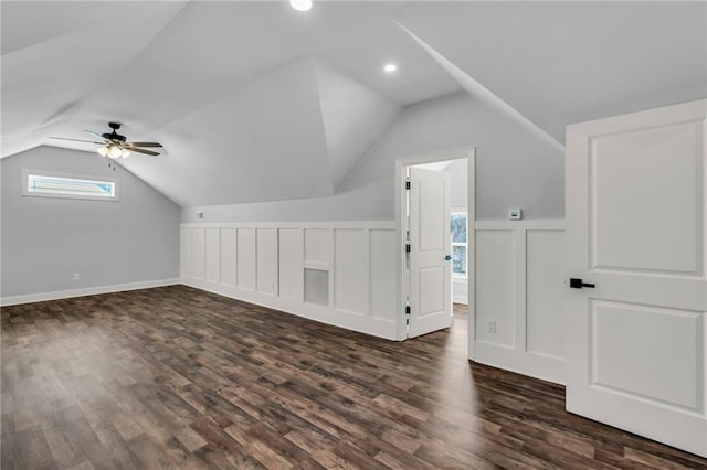 additional living space with dark wood-style floors, lofted ceiling, a decorative wall, and a ceiling fan