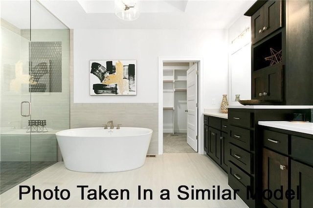 bathroom with vanity, separate shower and tub, and tile walls