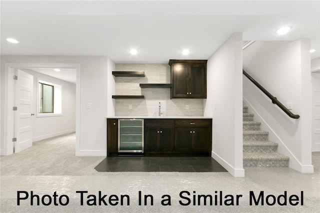 bar with sink, wine cooler, dark brown cabinetry, and decorative backsplash