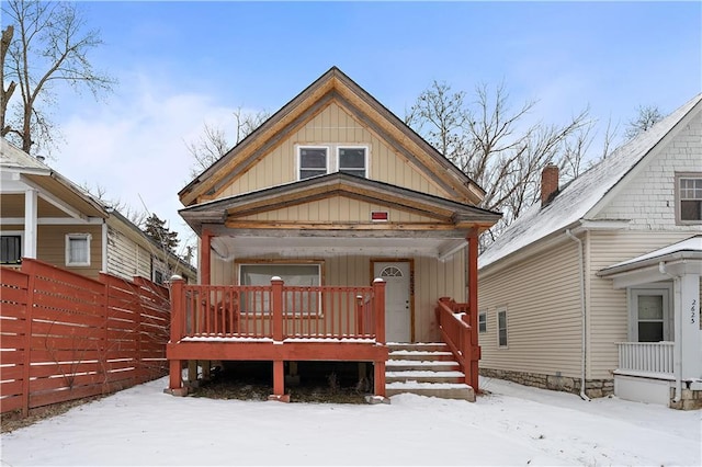 view of front of home featuring board and batten siding, covered porch, and fence