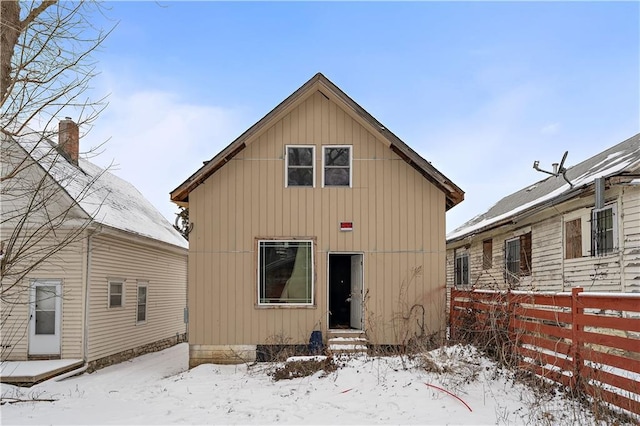 snow covered property with entry steps and fence