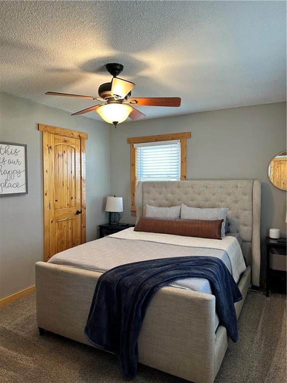 bedroom featuring a textured ceiling, carpet flooring, a ceiling fan, and baseboards