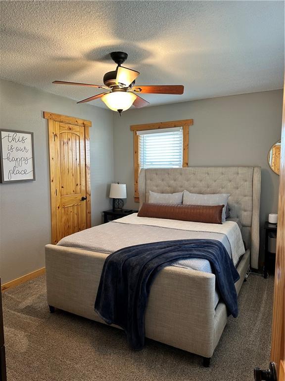 carpeted bedroom featuring a ceiling fan, a textured ceiling, and baseboards