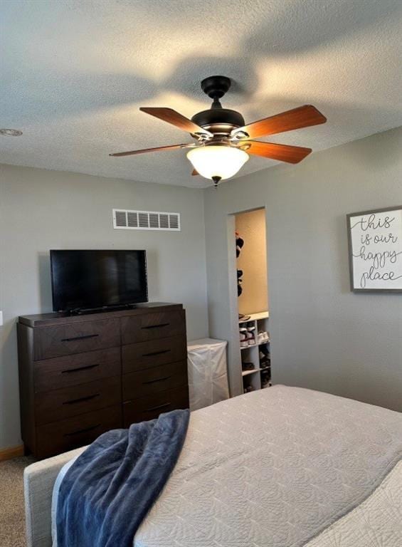 bedroom with carpet, visible vents, a ceiling fan, a textured ceiling, and baseboards