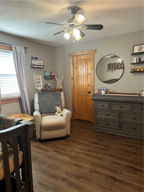 bedroom with a textured ceiling, ceiling fan, and dark wood-style flooring