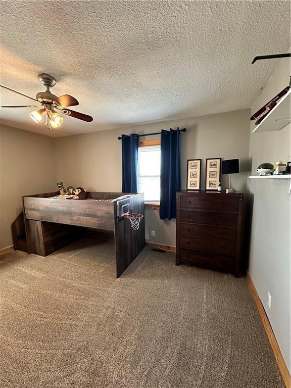 carpeted bedroom featuring ceiling fan, a textured ceiling, and baseboards