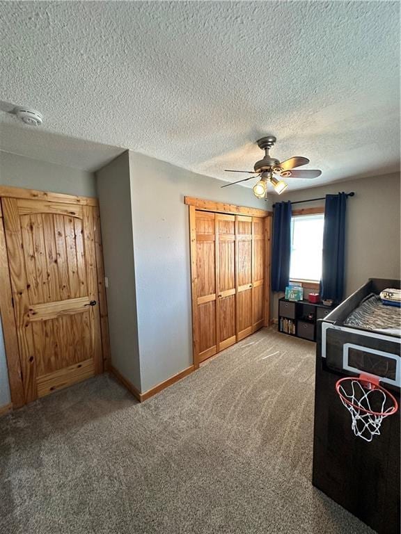 carpeted bedroom with a textured ceiling, a closet, baseboards, and a ceiling fan