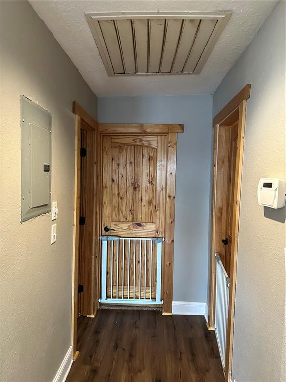 corridor with baseboards, electric panel, visible vents, and wood finished floors