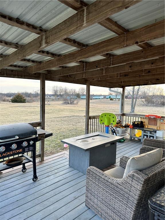 wooden deck with a rural view and a grill