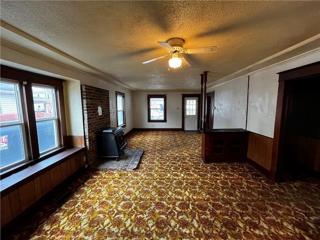 interior space featuring dark colored carpet, ornamental molding, a textured ceiling, and wood walls