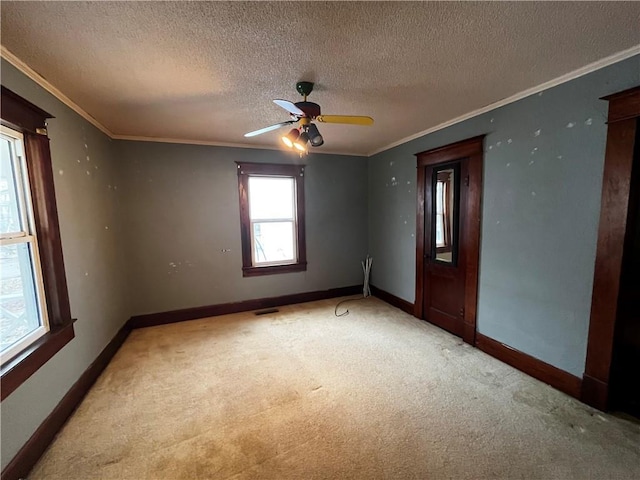 carpeted empty room featuring ornamental molding, ceiling fan, and a textured ceiling