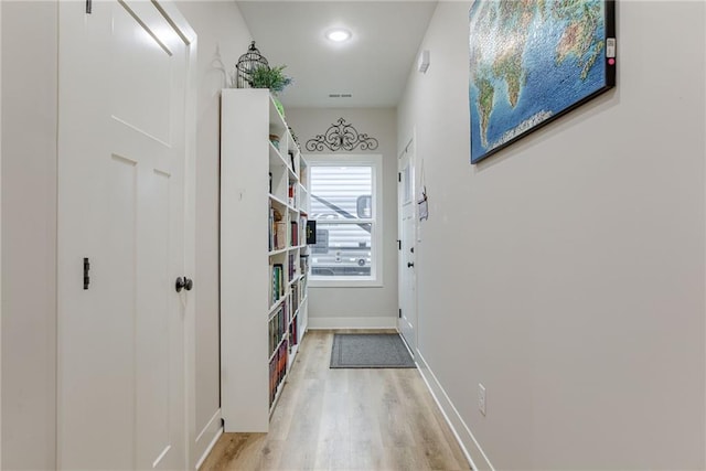 doorway with light wood finished floors, visible vents, and baseboards