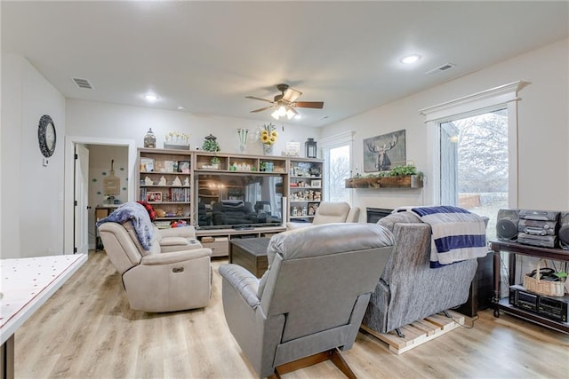 living room with plenty of natural light, light wood-type flooring, visible vents, and a fireplace