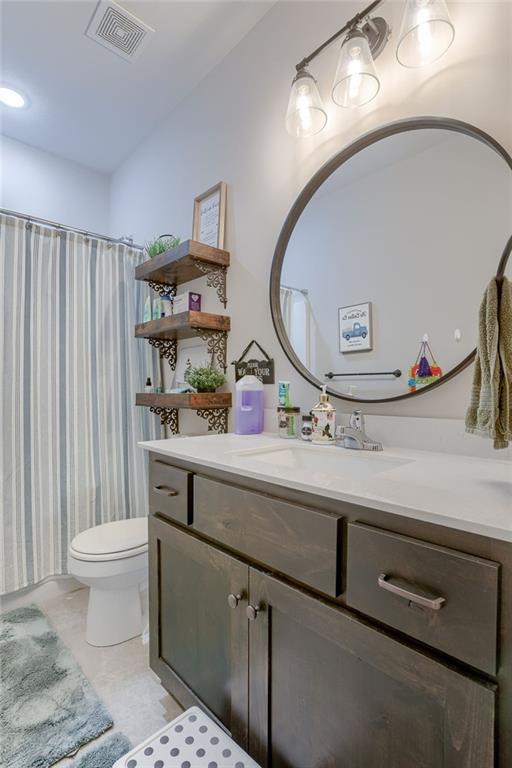 bathroom featuring toilet, vanity, and visible vents