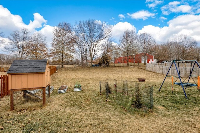 view of yard featuring a trampoline, fence, a playground, and an outdoor structure