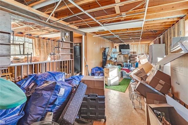 basement with black refrigerator and wood walls