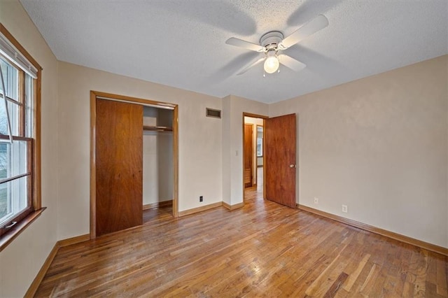 unfurnished bedroom with ceiling fan, light hardwood / wood-style floors, a closet, and a textured ceiling