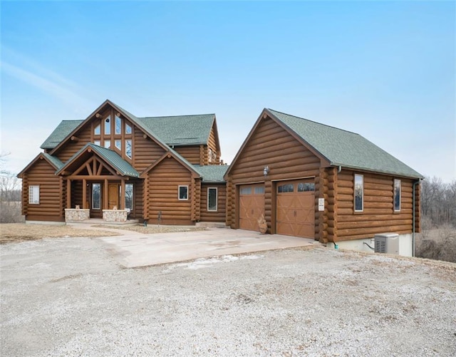 log cabin featuring covered porch, concrete driveway, and log siding