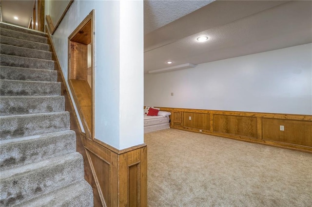 3812 SW Windemere Dr, Lees Summit, MO 64082 - stairs with carpet floors, a wainscoted wall, a textured ceiling, and recessed lighting