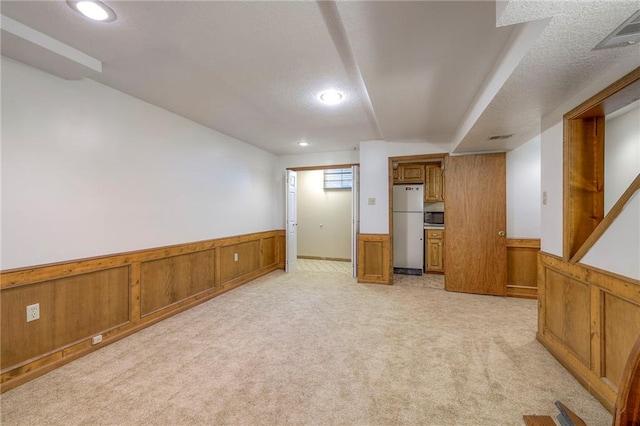 3812 SW Windemere Dr, Lees Summit, MO 64082 - finished basement featuring freestanding refrigerator, a wainscoted wall, light colored carpet, recessed lighting, and a textured ceiling