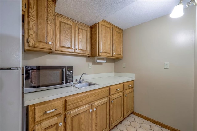 3812 SW Windemere Dr, Lees Summit, MO 64082 - kitchen featuring stainless steel microwave, freestanding refrigerator, light countertops, a textured ceiling, and brown cabinets