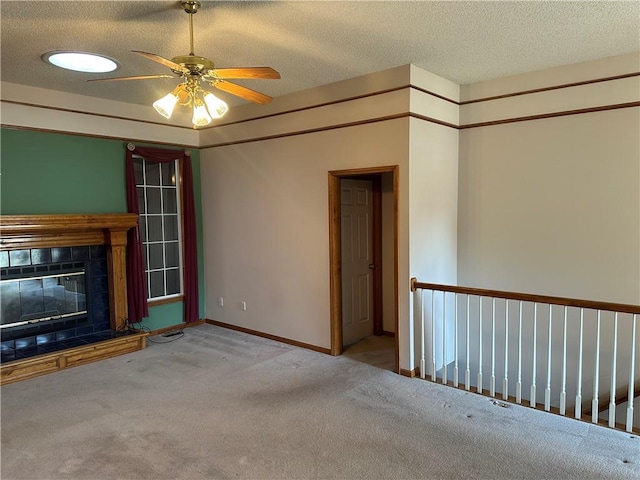 unfurnished living room with ceiling fan, light colored carpet, a textured ceiling, and a fireplace