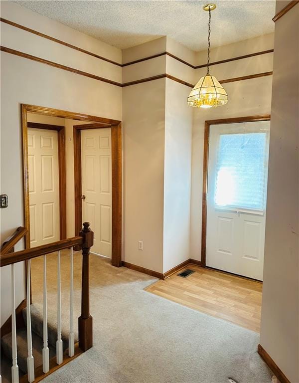 entryway featuring light carpet and a textured ceiling