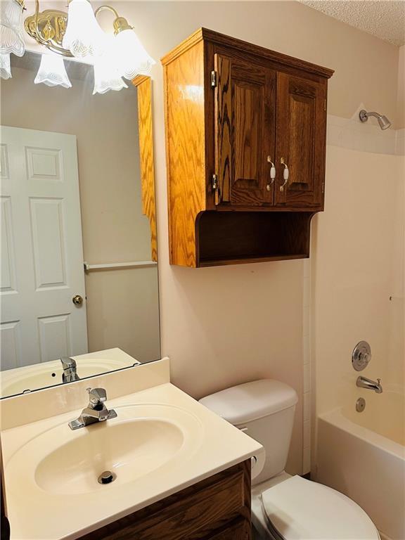 full bathroom featuring shower / bathing tub combination, vanity, toilet, and a textured ceiling