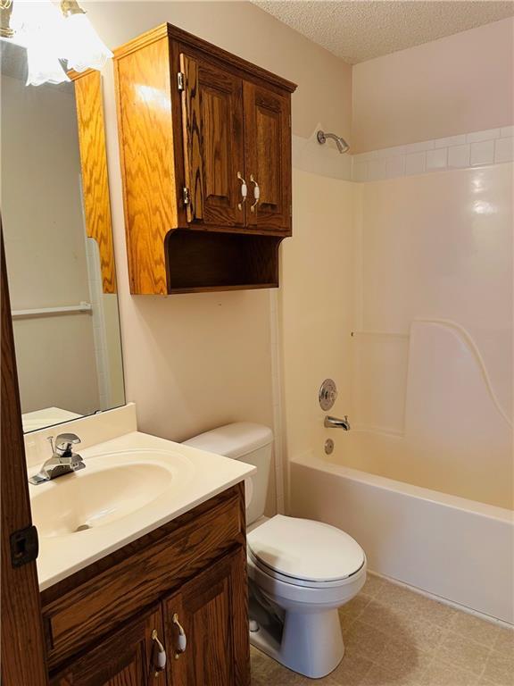 full bathroom with shower / bath combination, vanity, a textured ceiling, and toilet