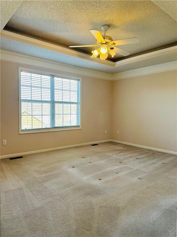 carpeted spare room featuring a raised ceiling, ornamental molding, ceiling fan, and a textured ceiling