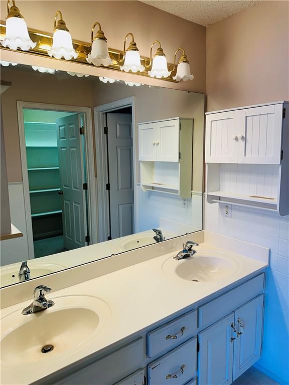 bathroom featuring vanity, a textured ceiling, and tile walls