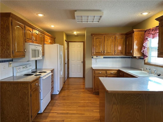 kitchen featuring tasteful backsplash, sink, kitchen peninsula, white appliances, and light hardwood / wood-style flooring