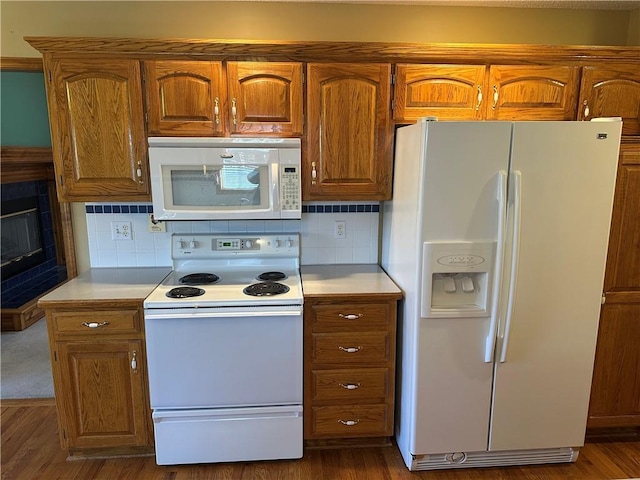 kitchen with tasteful backsplash, white appliances, and dark hardwood / wood-style flooring