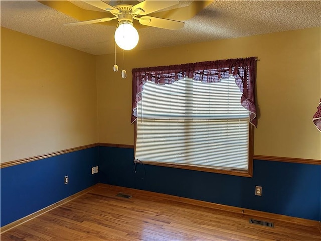 empty room with ceiling fan, hardwood / wood-style floors, and a textured ceiling