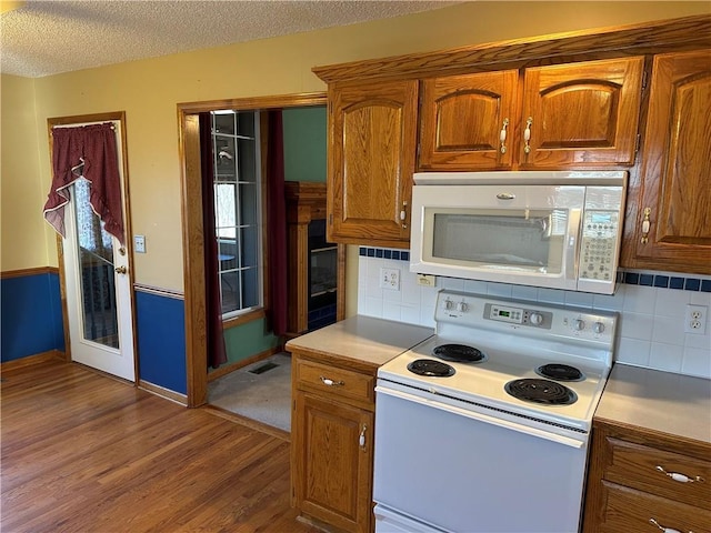 kitchen with white appliances, wood-type flooring, a textured ceiling, and backsplash